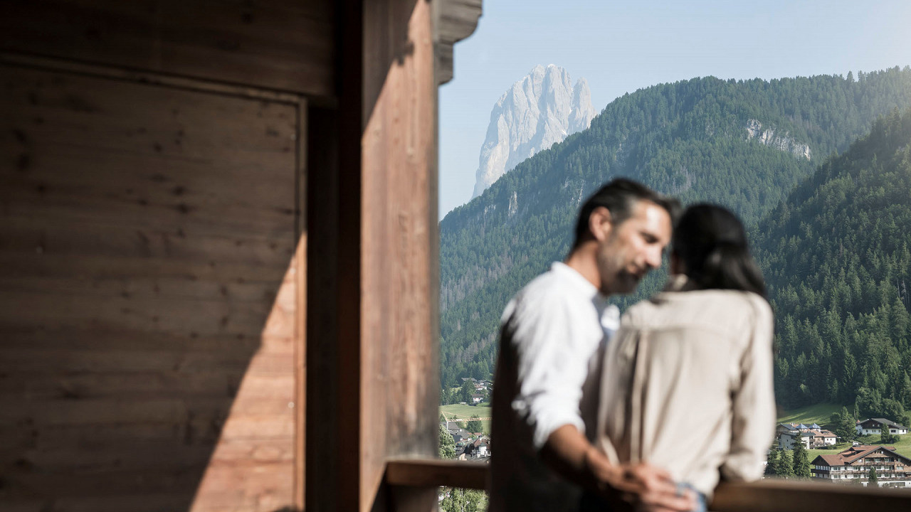 Coppia sul balcone di una camera che ammira il paesaggio ADLER Spa Resort DOLOMITI